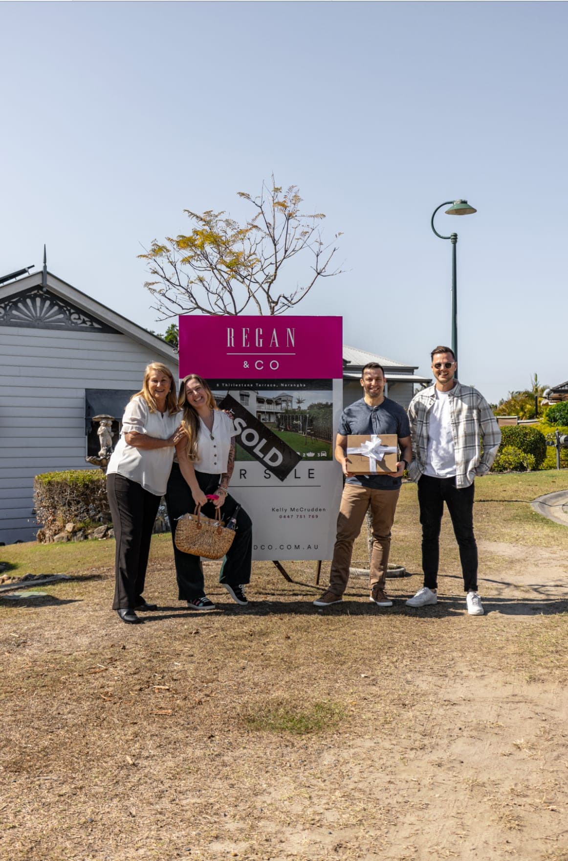 Buyers Collective clients and team celebrating at the sold sign of their new Brisbane home